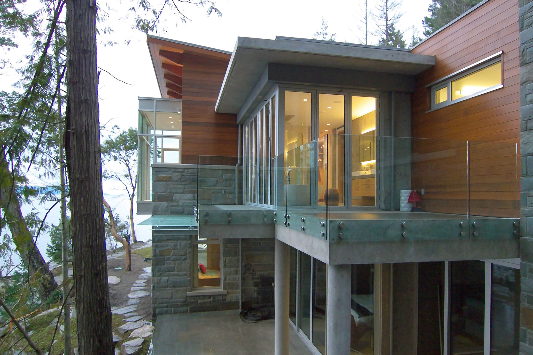 Cantilevered glazed volume among the cedars