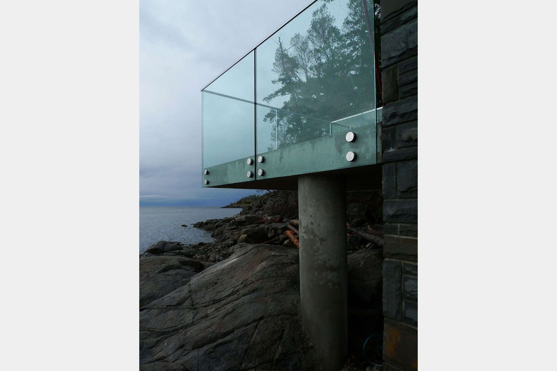 Glass balustrade carried on a concrete column over the rocky foreshore
